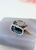 bague cocktail centrée d'une topaze facetée serti clos entourée de petits diamants et de saphirs sur le panier or 750 millième (18