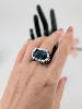 bague cocktail centrée d'une topaze facetée serti clos entourée de petits diamants et de saphirs sur le panier or 750 millième (18