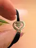bracelet sur cordon noir orné d'un motif coeur o.j perrin légendes en or blanc or 750 millième (18 ct) 2,51g