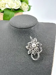 broche fleur en métal argenté ornée des strass centrée d'une perle synthétique