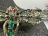 broche libellule en métal doré ornée des strass verts, blancs et roses