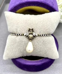 bracelet ligne cristaux gucci en métal couleur or vieilli avec logo gg et motif abeill et perle synthétique en forme goutte d'eau 