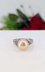 bague en or blanc orcentrée d'une perle de l'eau de mer d'environ 10,7mm couleur beige épaulée de motifs feuilles pavées de petits