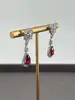 boucles d'oreilles pendantes chacune centrée d'une pierre rouge entouré d'oxydes