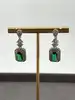 boucles d'oreilles pendantes chacune centrée d'une pierre verte entouré d'oxydes