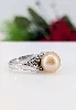 bague en or blanc orcentrée d'une perle de l'eau de mer d'environ 10,7mm couleur beige épaulée de motifs feuilles pavées de petits