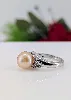 bague en or blanc orcentrée d'une perle de l'eau de mer d'environ 10,7mm couleur beige épaulée de motifs feuilles pavées de petits