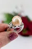 bague en or blanc orcentrée d'une perle de l'eau de mer d'environ 10,7mm couleur beige épaulée de motifs feuilles pavées de petits