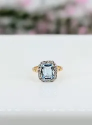 bague en or blanc style art-déco centrée d'une topaze bleue taille émeraude entourée de diamants taille rose or 750 millième (18 c