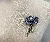broche fleur en métal doré ornée des strass colorés centrée d'une perle synthétique