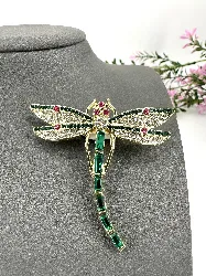 broche libellule en métal doré ornée des strass verts, blancs et roses