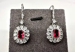 boucles d'oreilles pendantes chacune centrée d'une pierre rose entourée d'oxydes