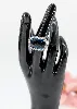 bague cocktail centrée d'une topaze facetée serti clos entourée de petits diamants et de saphirs sur le panier or 750 millième (18