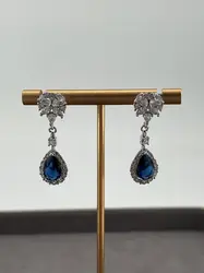 boucles d'oreilles pendantes chacune centrée d'une pierre bleue