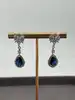 boucles d'oreilles pendantes chacune centrée d'une pierre bleue