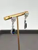 boucles d'oreilles pendantes chacune centrée d'une pierre bleue