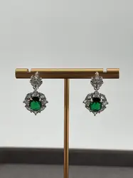 boucles d'oreilles pendantes chacune centrée d'une pierre verte entouré d'oxydes