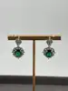 boucles d'oreilles pendantes chacune centrée d'une pierre verte entouré d'oxydes