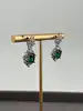 boucles d'oreilles pendantes chacune centrée d'une pierre verte entouré d'oxydes